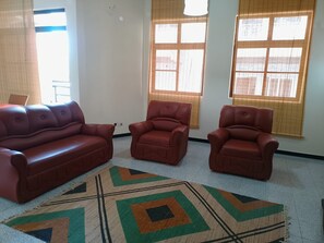 Ein Wohnzimmer mit einer Couch, zwei Sesseln und einem gemusterten Teppich.