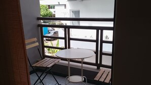 Un balcon avec une petite table ronde et deux chaises en bois.