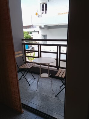 Ein Balkon mit einem kleinen runden Tisch und zwei Holzstühlen.