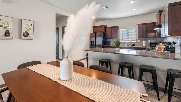 A modern kitchen with dark wooden cabinets, a granite countertop, and a central island with bar stools. - Modern 2BR/2BA Home • King Bed • Smart TVs (D) (El Paso)