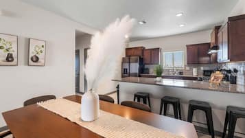 A modern kitchen with dark wooden cabinets, a granite countertop, and a central island with bar stools.