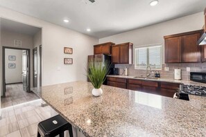 Eine Küche mit Granit-Arbeitsplatten, Holzschränken, einem Edelstahl-Kühlschrank und einem schwarzen Herd.