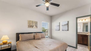 A bedroom with a bed, a nightstand, a lamp, a ceiling fan, and artwork on the walls. - Modern 2BR/2BA Home • King Bed • Smart TVs (D) (El Paso)