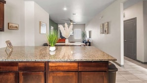 A kitchen with a granite countertop, wooden cabinets, and a ceiling fan. - Modern 2BR/2BA Home • King Bed • Smart TVs (D) (El Paso)