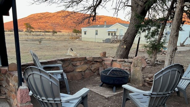 Une terrasse avec deux chaises, un foyer et un mur en pierre.