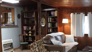 Un salon chaleureux avec un canapé en cuir marron, un fauteuil à motifs, une bibliothèque et une petite table.