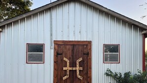 Un bâtiment d’un seul étage, doté d’une façade en métal ondulé et d’une porte double en bois ornée d’une croix.