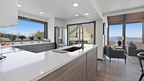A modern kitchen with a large island, built-in appliances, and large windows offering a view of the outdoors. - Best View in Beech Mountain ski in, ski out, sauna (Beech Mountain)