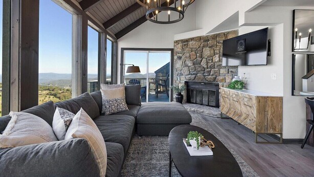 A modern living room with a large sectional sofa, a coffee table, and a stone fireplace. - Best View in Beech Mountain ski in, ski out, sauna (Beech Mountain)
