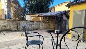 An outdoor patio with stone flooring, metal chairs, and a table.