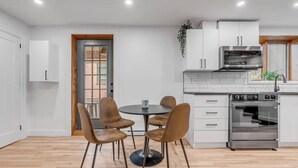 Cozinha moderna com armários brancos, forno embutido e sala de jantar com mesa redonda e quatro cadeiras.