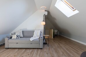A loft-style room with a gray sofa, a standing lamp, and a skylight. - Adorable 1-bedroom apartment with AC in charming Québec (Québec)