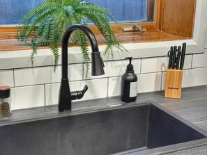 A kitchen with a black faucet, a soap dispenser, and a knife block. - Adorable 1-bedroom apartment with AC in charming Québec (Québec)