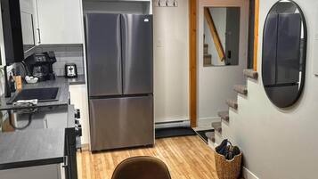 A compact kitchen with a stainless steel refrigerator, a coffee maker, and a toaster.