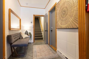 A hallway with a bench, a rug, a wall-mounted mirror, a door with a decorative panel, and a staircase. - Adorable 1-bedroom apartment with AC in charming Québec (Québec)