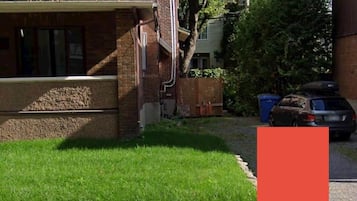 A two-story building with a green roof, brick exterior, and a small front yard with grass.