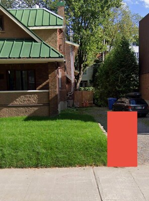 A two-story building with a green roof, brick exterior, and a small front yard with grass. - Adorable 1-bedroom apartment with AC in charming Québec (Québec)