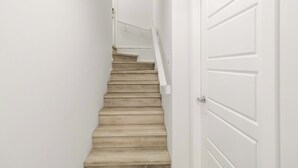 Eine Treppe mit Handlauf, weißen Wänden und einer Tür.