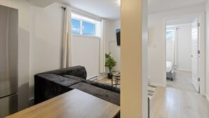 Ein modernes Wohnzimmer mit einer Couch, einem Holztisch und einem an der Wand montierten Fernseher.