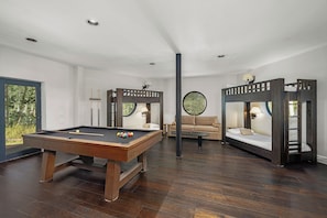 A room with a pool table, two bunk beds, a sofa, and a circular window. - NEW! Luxury Family & Group Retreat | Hot Tub, Gym + Mountain Views | Sleeps 14 (Telluride)