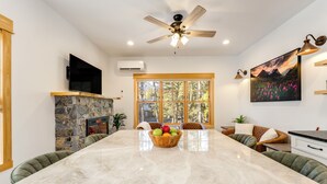 A spacious kitchen with a large island, stone fireplace, and a large window with a mountain view.