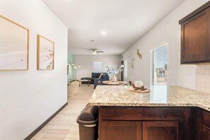 Una cocina con encimera de granito, armarios oscuros y un bote de basura.