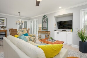 A living room with a sofa, coffee table, and a TV in the background. - Cozy 1BR King suite in Palmetto Dunes, Hilton Head Island, perfect for couples! (Hilton Head Island)