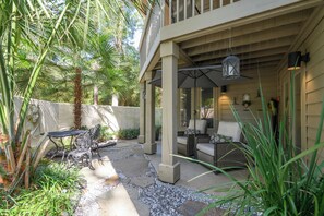 A covered patio area with outdoor furniture, a stone pathway, and lush greenery. - Cozy 1BR King suite in Palmetto Dunes, Hilton Head Island, perfect for couples! (Hilton Head Island)