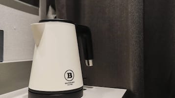 A white electric kettle with a black handle and a logo on the base, placed on a white surface.