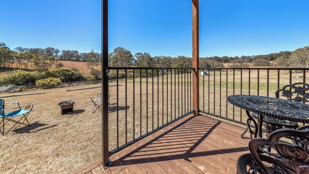 A wooden deck with a metal railing, a table, and chairs. - Glamping @ Undercliff Farm (Undercliffe)