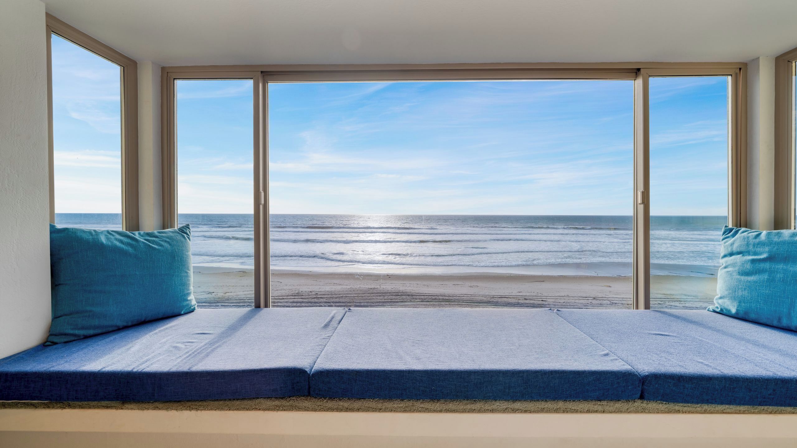 Una habitación con un ventanal grande con vistas a la playa.