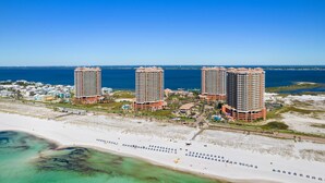 Een kusthotel met drie hoge gebouwen, directe toegang tot het strand en een helder uitzicht op de oceaan.
