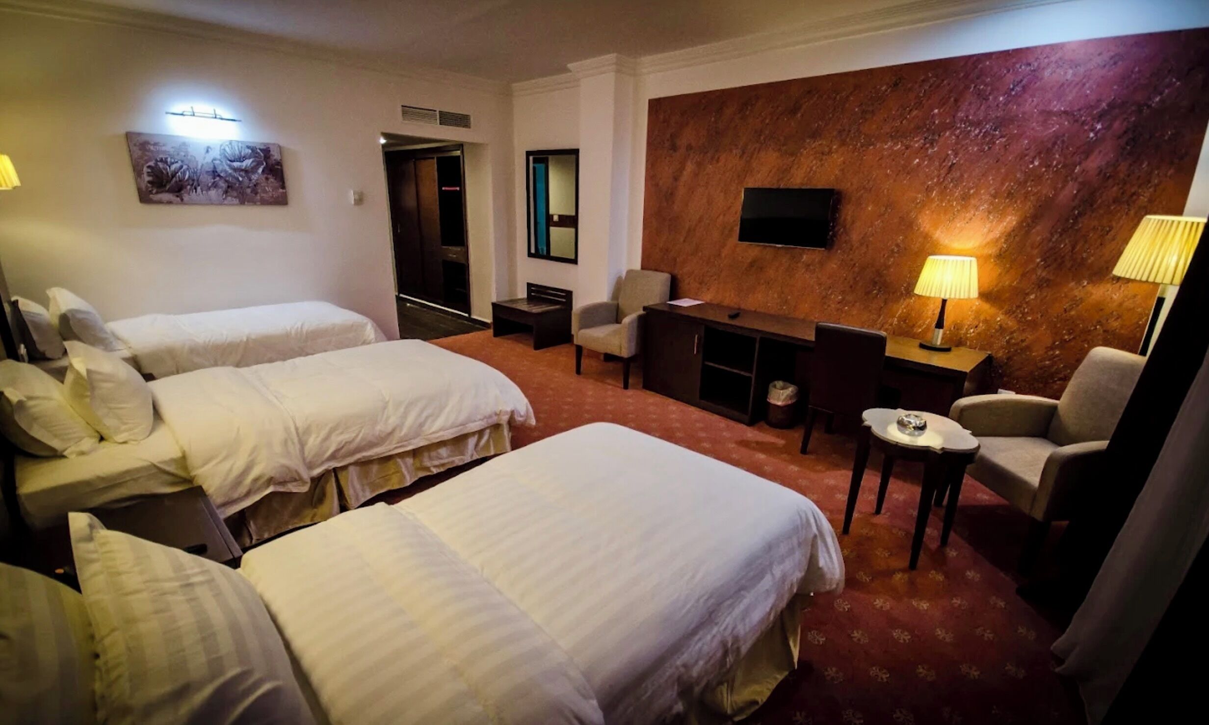 Una habitación de hotel con dos camas, un escritorio, una silla, un televisor y una lámpara.