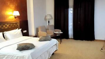 Una habitación de hotel con una cama, dos sillas, una mesita y una lámpara.