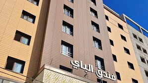 Un hotel moderno con varios pisos, una entrada destacada con celosías decorativas y varias ventanas.