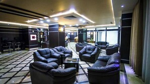 Un vest íbulo con sofás de cuero, una mesa de recepción y piso de baldosas.
