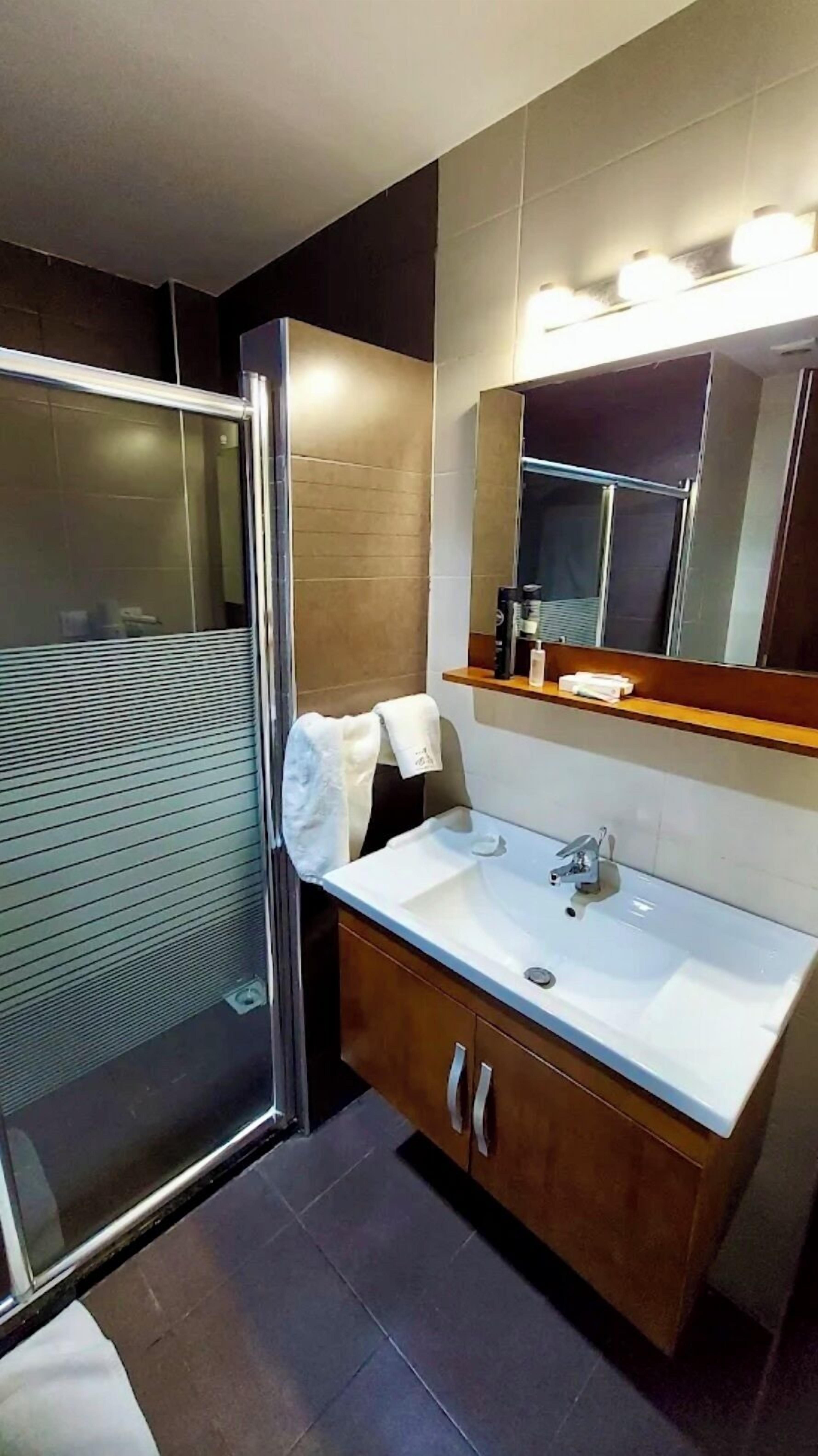 A modern bathroom with a glass shower enclosure, a vanity with a mirror, and a sink.