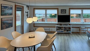 Une pièce comprenant une grande table ovale, plusieurs chaises, un téléviseur et une bibliothèque.