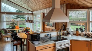 A kitchen with a stove, oven, and coffee maker. There is a dining table with chairs and a window with curtains. - Nice home in Rødvig Stevns with WiFi (Rødvig Stevns)