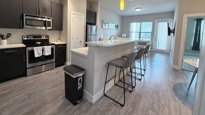 Una cocina moderna con electrodomésticos de acero inoxidable, una isla central con taburetes y vista al área de estar.