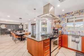 A modern kitchen with a central island, a dining area with chairs, and a colorful backsplash. - Diamond Oasis - Old Town, ASU - Heated Pool, Spa (Scottsdale)
