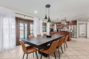A modern kitchen with stainless steel appliances, a dining area with a large table and chairs, and a view of a swimming pool through the glass doors. - Diamond Oasis - Old Town, ASU - Heated Pool, Spa (Scottsdale)