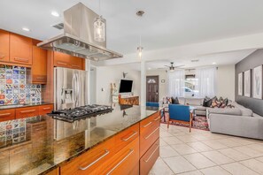 A modern kitchen with a central island, stainless steel appliances, and a dining area with a sofa and chairs. - Diamond Oasis - Old Town, ASU - Heated Pool, Spa (Scottsdale)