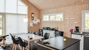 A modern kitchen with wooden walls, a dining area with a glass table, and a coffee machine. - Gorgeous home in Tarm with sauna (Tarm)