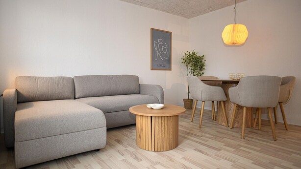 Ein modernes Wohnzimmer mit grauem Sofa, einem Holztisch und einem Essbereich mit Holztisch und vier Stühlen.
