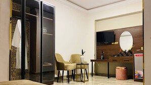 A hotel room with a bed, a seating area with two chairs, a desk with a mirror, and a wardrobe. - MARQUIS PYRAMIDS HOTEL (Giza)