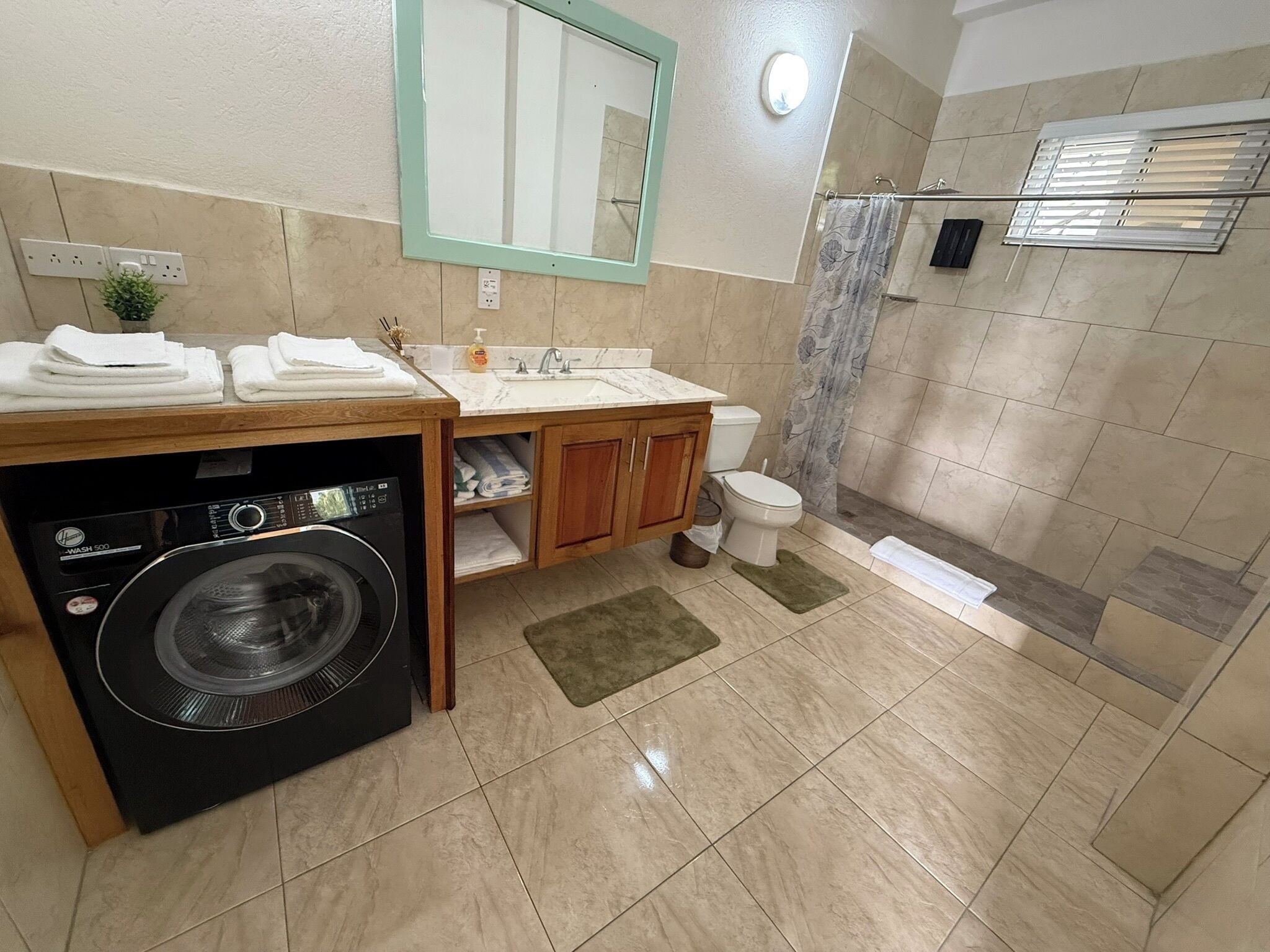 Une salle de bain équipée d’un lave-linge, de toilettes, d’un lavabo et d’un espace douche.