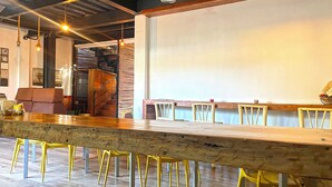 Un grand espace bar avec un long comptoir en bois et des chaises jaunes.