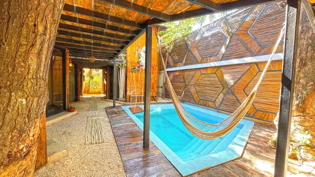 Un espace piscine agrémenté d’un hamac, d’un sol en bois et d’un mur orné d’un motif hexagonal.