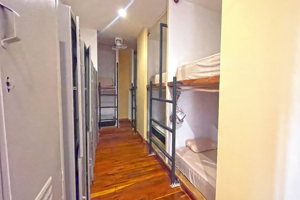 A narrow hallway with bunk beds on one side and a door at the end.